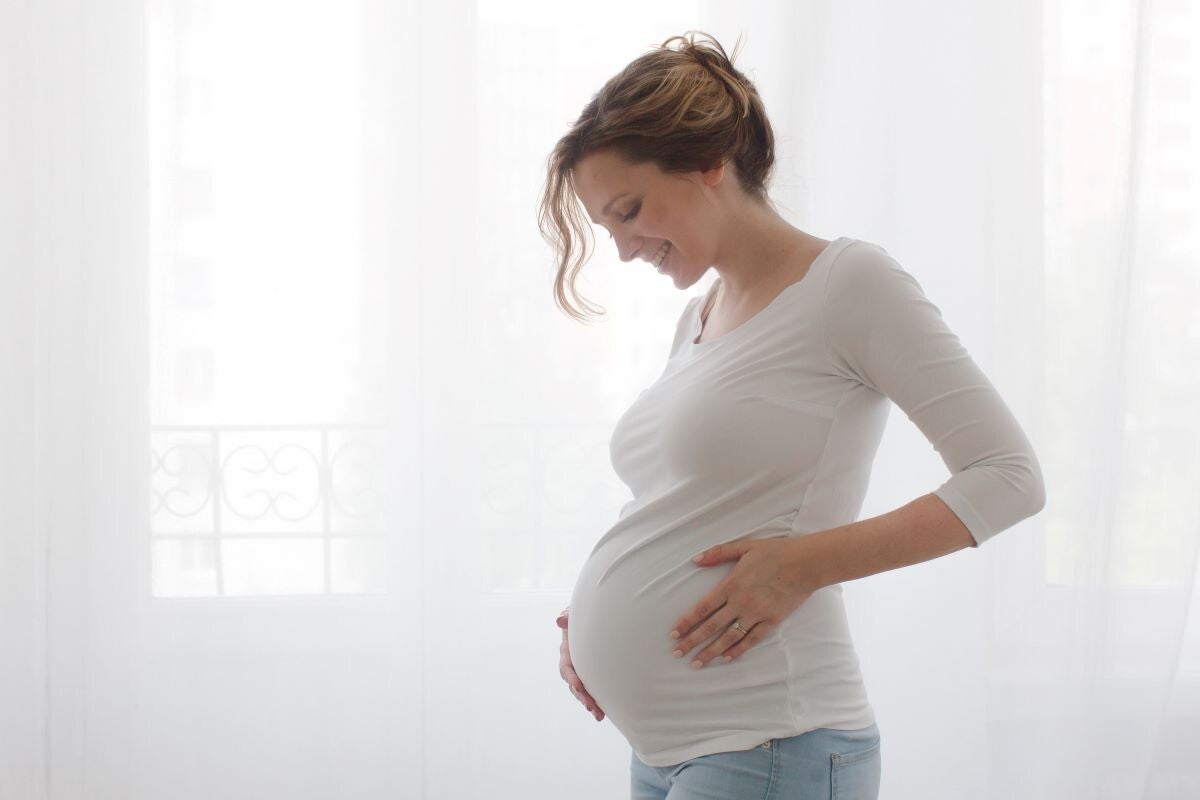 Schwangere Frau schaut glücklich auf ihren Bauch