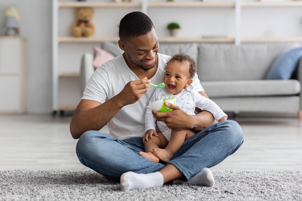 Baby zufüttern-Papa füttert lachendes Baby