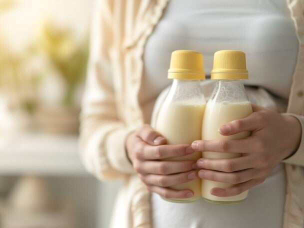 Mutter hält zwei volle Flaschen mit Muttermilch in den Händen.