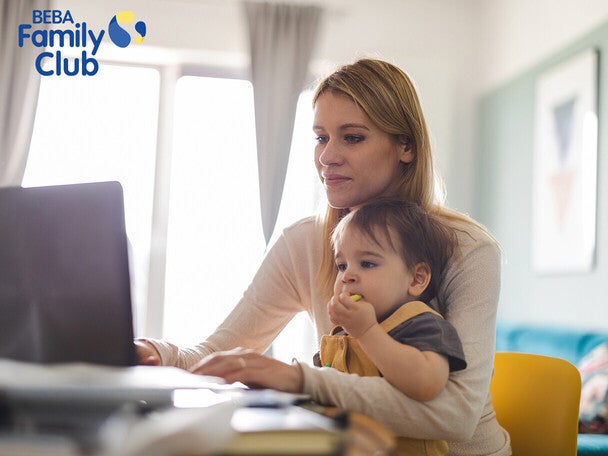 Mama mit Kind auf dem Schoß und am Laptop arbeiten