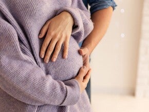 Schwangere hält schützend die Hand über ihren Bauch