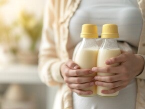 Mutter hält zwei volle Flaschen mit Muttermilch in den Händen.