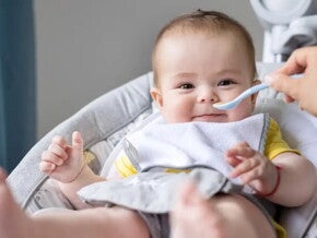 Baby zufüttern-Lachendes Baby in Babyschale