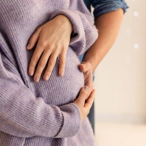 Schwangere hält schützend die Hand über ihren Bauch