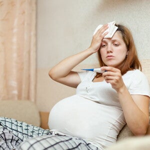 Schwangere Frau hält Fieberthermometer Schwangere Frau hält Fieberthermometer