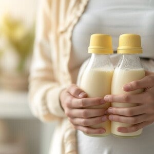 Mutter hält zwei volle Flaschen mit Muttermilch in den Händen.