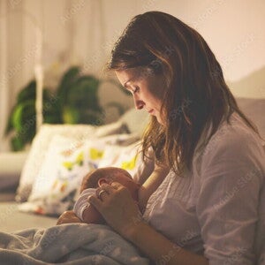 Clusterfeeding: junge Mutter stillt nachts ihr Baby Clusterfeeding: junge Mutter stillt nachts ihr Baby