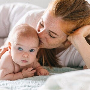 Mutter umarmt ihr Neugeborenes im Bett. Vier Monate altes Baby.