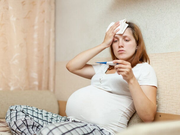 Schwangere Frau hält Fieberthermometer