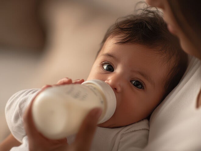 Baby mit Flasche auf Arm der Mutter