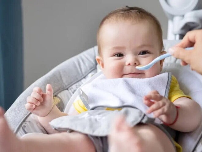 Baby zufüttern-Lachendes Baby in Babyschale