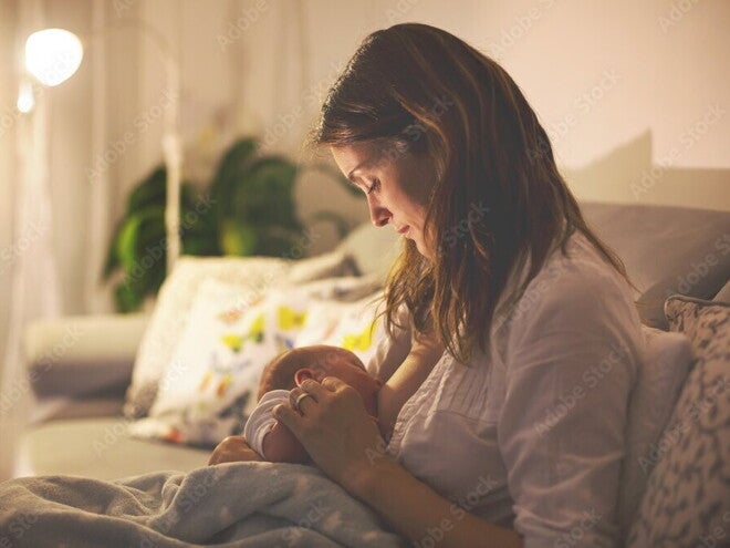 Clusterfeeding: junge Mutter stillt nachts ihr Baby Clusterfeeding: junge Mutter stillt nachts ihr Baby