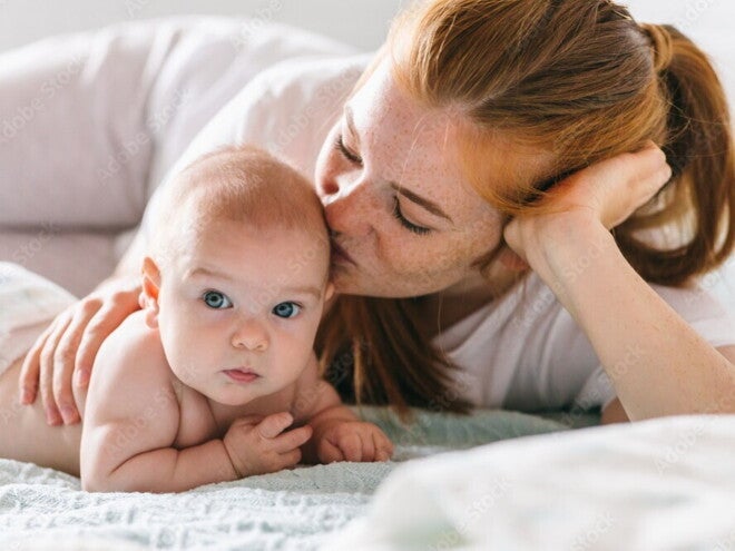 Mutter umarmt ihr Neugeborenes im Bett. Vier Monate altes Baby.