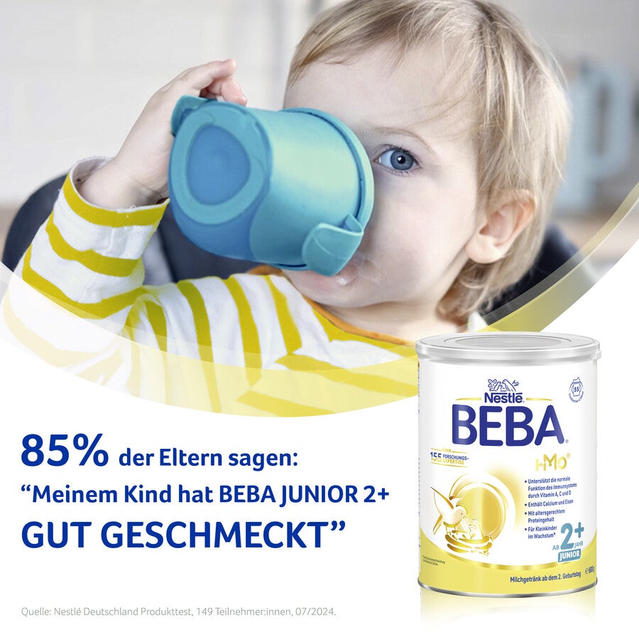Child holding blue cup next to Beba Junior milk powder container.