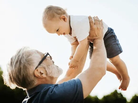 Ein glücklicher kleiner Junge mit Strohhut am See, stellvertretend für die Prognose der 10 beliebtesten Vornamen für Jungen 2025.