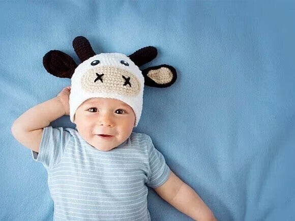 Baby mit gestrickter Kuhmütze – Illustration zum Thema Kuhmilchallergie beim Baby 