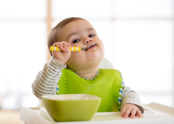 Baby zufüttern-Baby mit Löffel im Mund Baby zufüttern-Baby mit Löffel im Mund