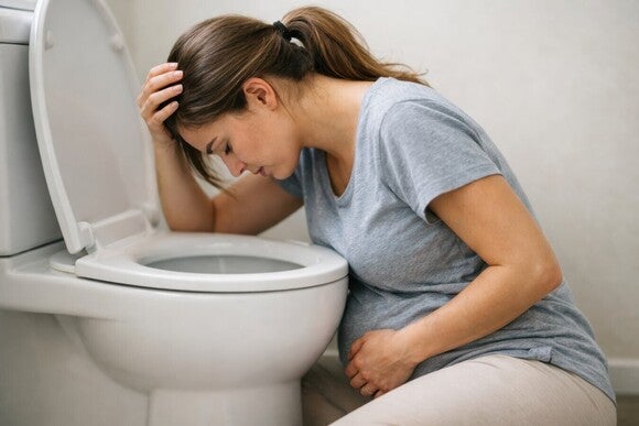 Schwangere Frau muss sich über der Toilette übergeben