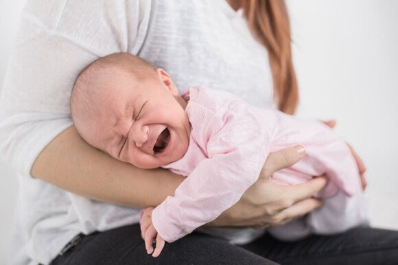 Mutter hält schreiendes Baby in beruhigender Position Mutter hält schreiendes Baby in beruhigender Position