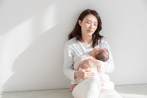 Mutter hält ihr Schreibaby erschöpft n den Armen 