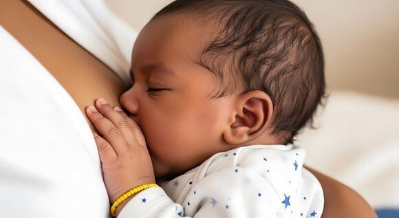 Baby hält die Brust der Mutter, während es die Augen schließt und gestillt wird.