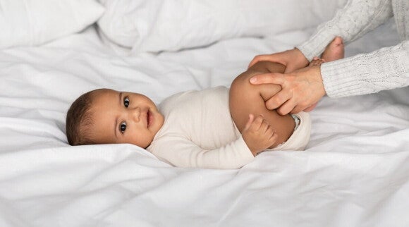 Mutter gibt ihrem Baby mit Verstopfung eine Bauchmassage Mutter gibt ihrem Baby mit Verstopfung eine Bauchmassage