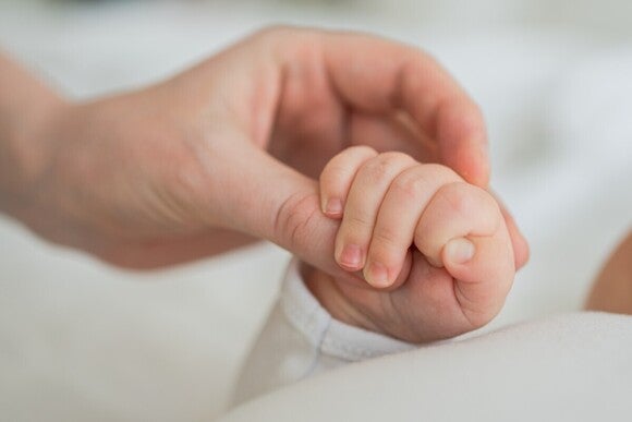 Die Hand des Babys wird von einem Erwachsenen gehalten.
