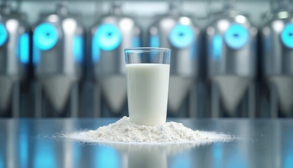 Eine Tasse voll mit Milch auf einem kleinen Haufen voll Babymilch Pulver auf einem Edelstahl Tisch gestellt.