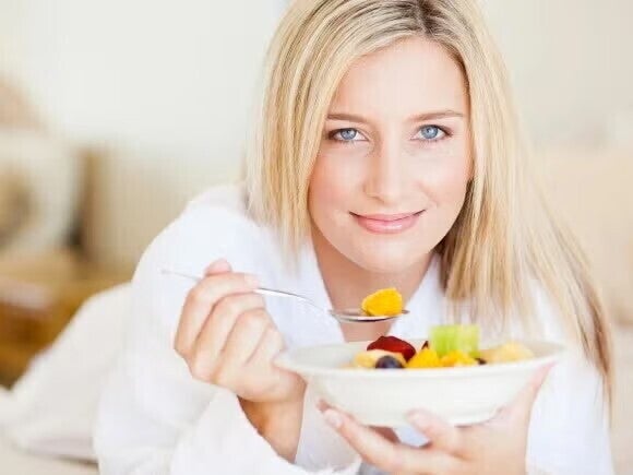 Eine Frau mit Kinderwunsch isst einen gesunden Obstsalat