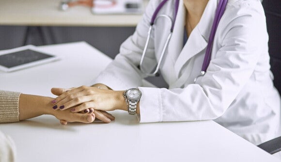 Eine Gynäkologin hält in einem Beratungsgespräch zur Fruchtbarkeit sanft die Hand einer Frau