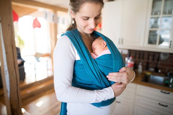 Eine Mutter hält ihr schlafendes Baby in einem Wickel vor ihrer Brust