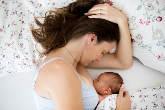 Frau stillt ihr Baby im Bett Frau stillt ihr Baby im Bett