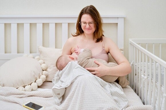 Stillende Mutter mit Baby auf dem Arm erfährt starke Schmerzen durch das Stillen.