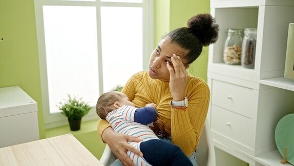 Mutter stillt ihr Baby auf dem Arm und versinkt währenddessen in Gedanken.
