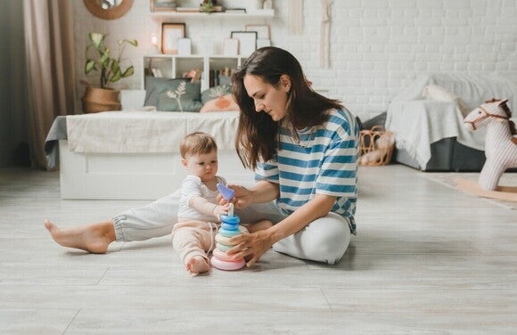 Mutter und Baby spielen auf dem Boden mit einem Stapelspielzeug