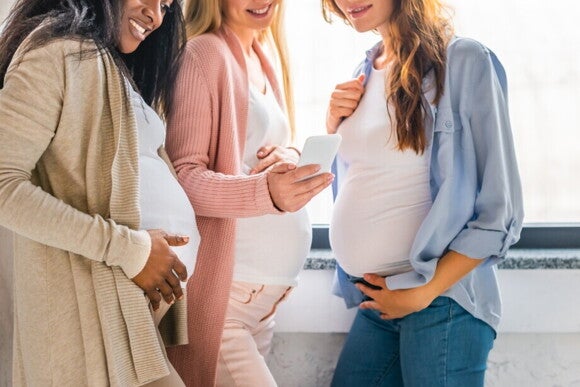 Schwangere Frauen schauen auf ein Smartphone Schwangere Frauen schauen auf ein Smartphone
