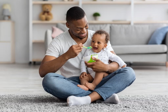 Baby zufüttern-Papa füttert lachendes Baby Baby zufüttern-Papa füttert lachendes Baby