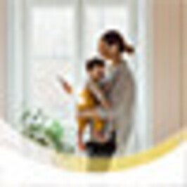 Frau vor einem Fenster mit ihrem Baby auf dem Arm