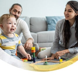 Familie sitzt auf dem Boden und spielt mit ihrem Baby und Spielzeug