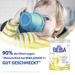 Child wearing striped shirt holding a blue cup; BEBA milk can in foreground.