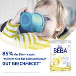 Child holding blue cup next to Beba Junior milk powder container.