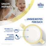 Baby holding bottle of milk with ingredients highlighted.
